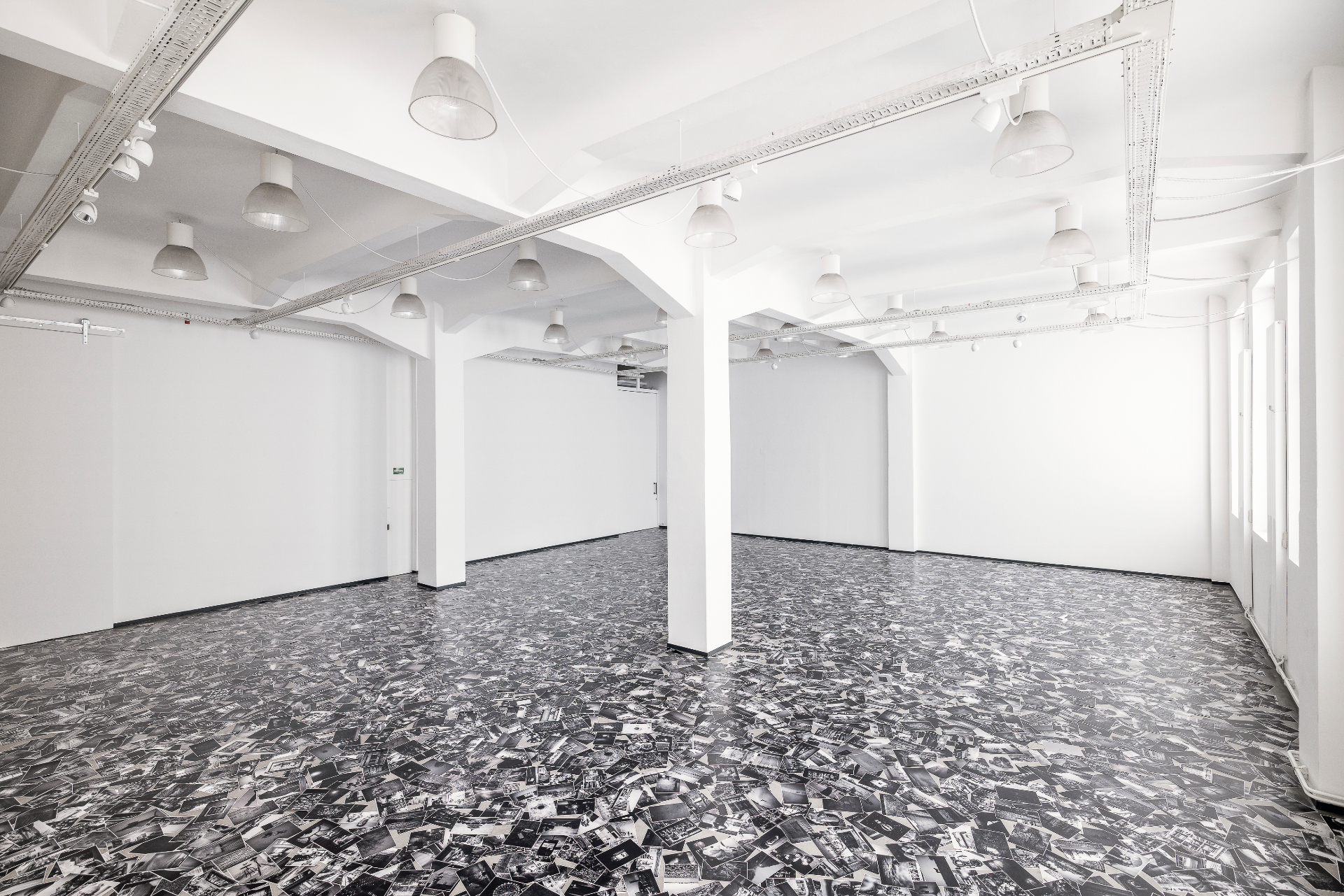 Installation view — empty hall and dense black-and-white floor collage