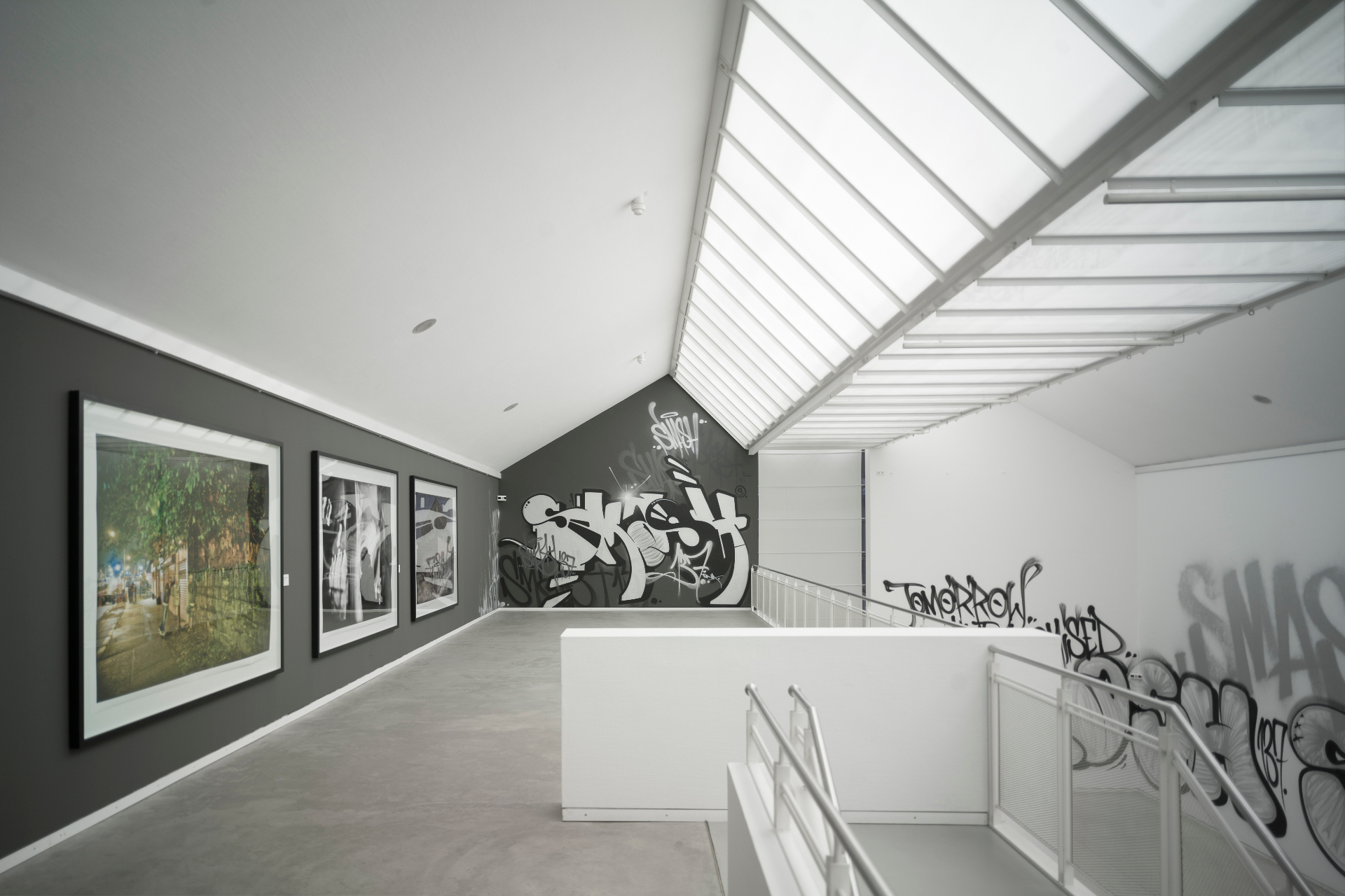 Installation view — upper level with framed works and graffiti intervention